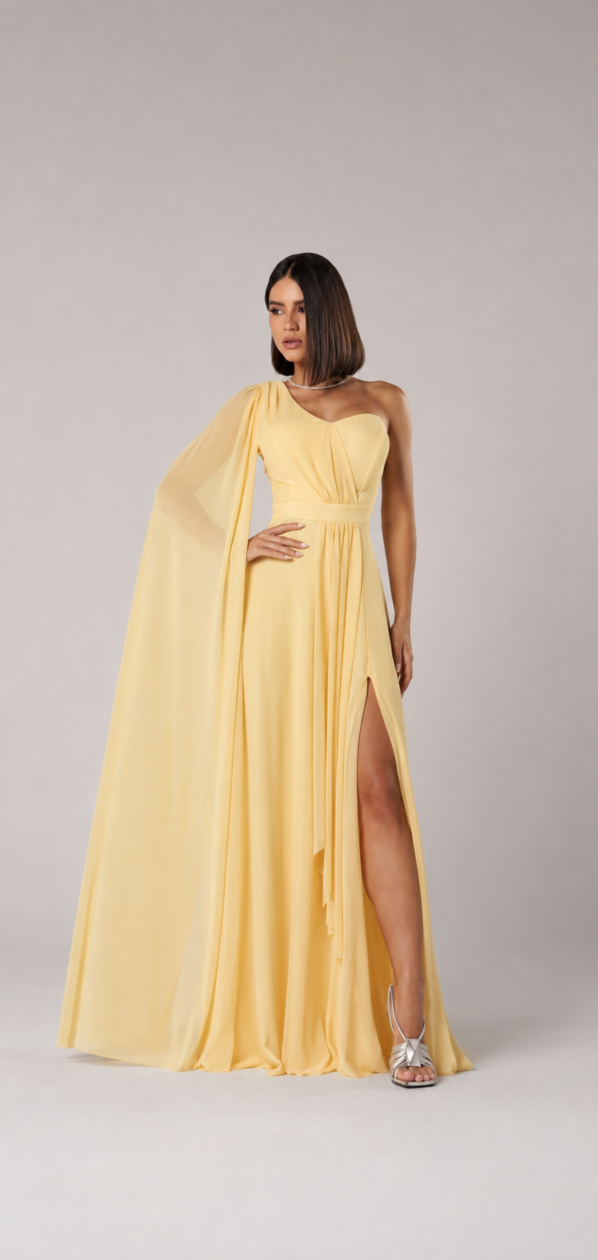 Vestido longo amarelo manteiga, de um ombro, com manga-capa e fenda